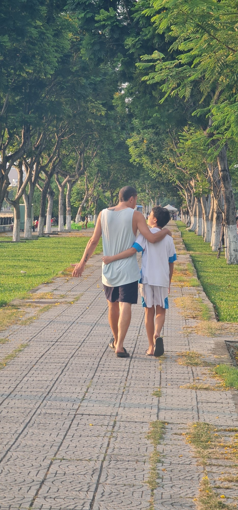 Father and child walk through sunny Đà Nẵng park