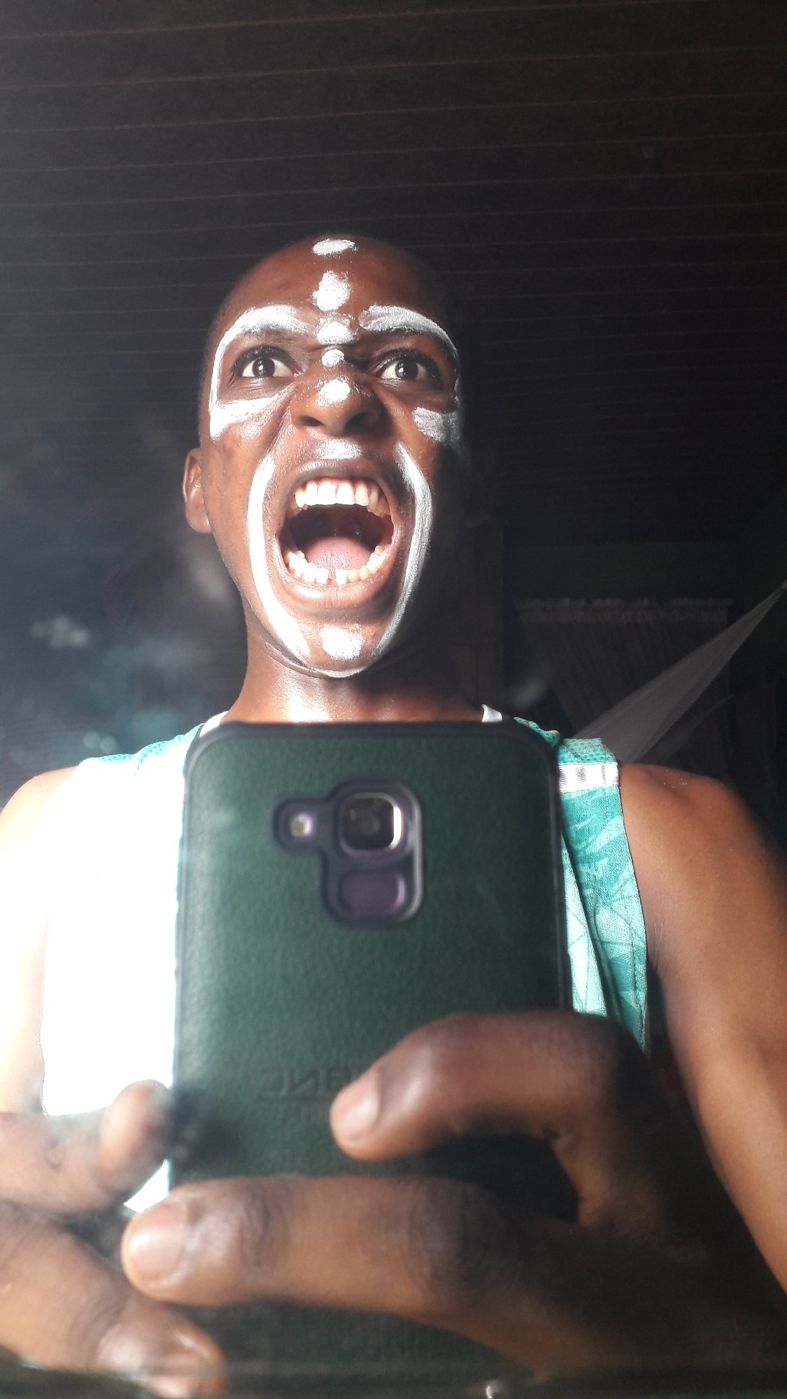 Person documents selfie session with ceremonial face paint in Nigeria