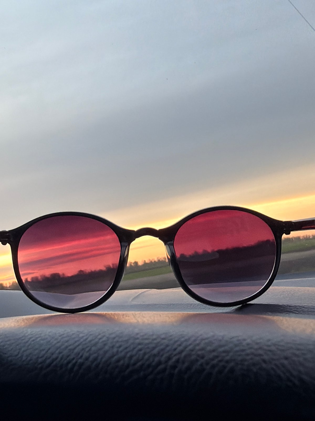 Rotated sunglasses reflect colorful sky in Alexandrovka, Russia