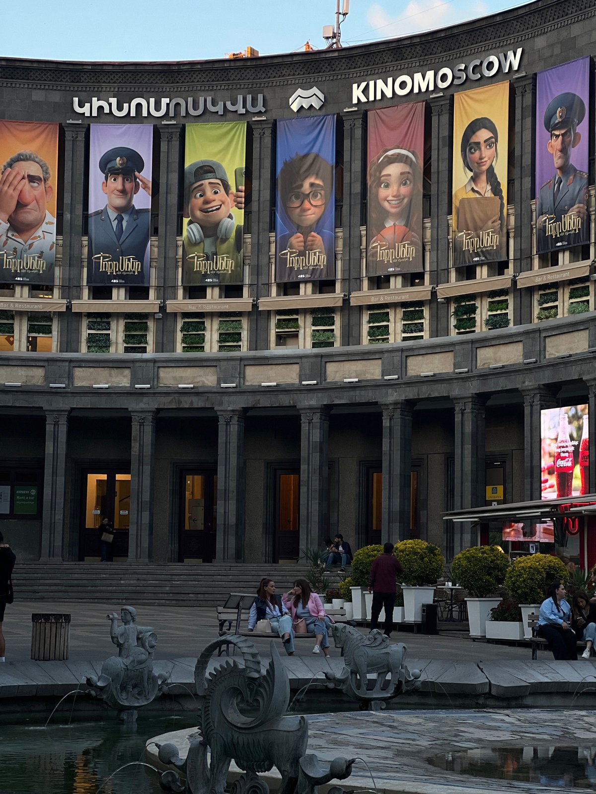 Urban scenes documented near KINOMOSCOW building with sculptures and cafés
