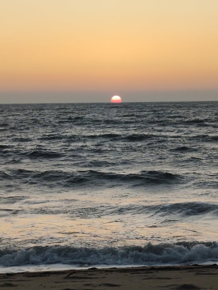 Sunset documented at Querim Beach, Goa with beachgoers and animals