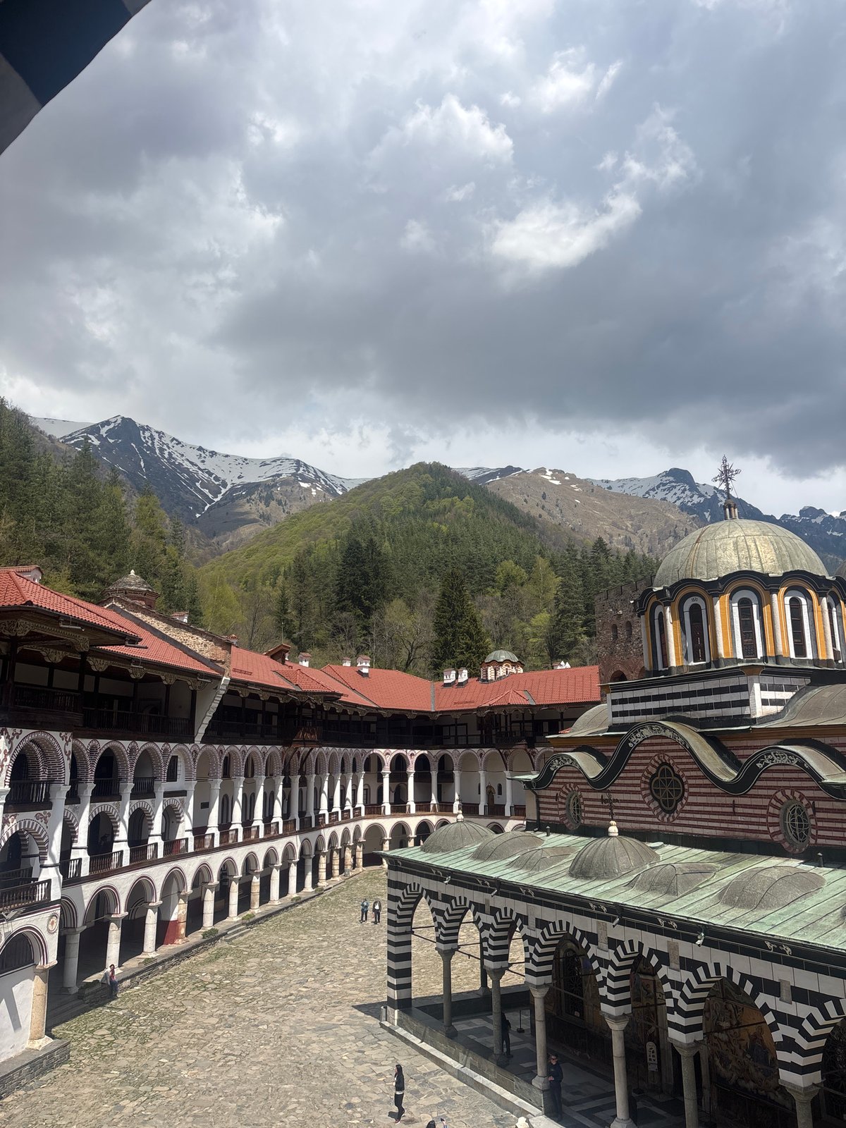 Visitor documents Rila Monastery views amid Bulgarian mountain landscape
