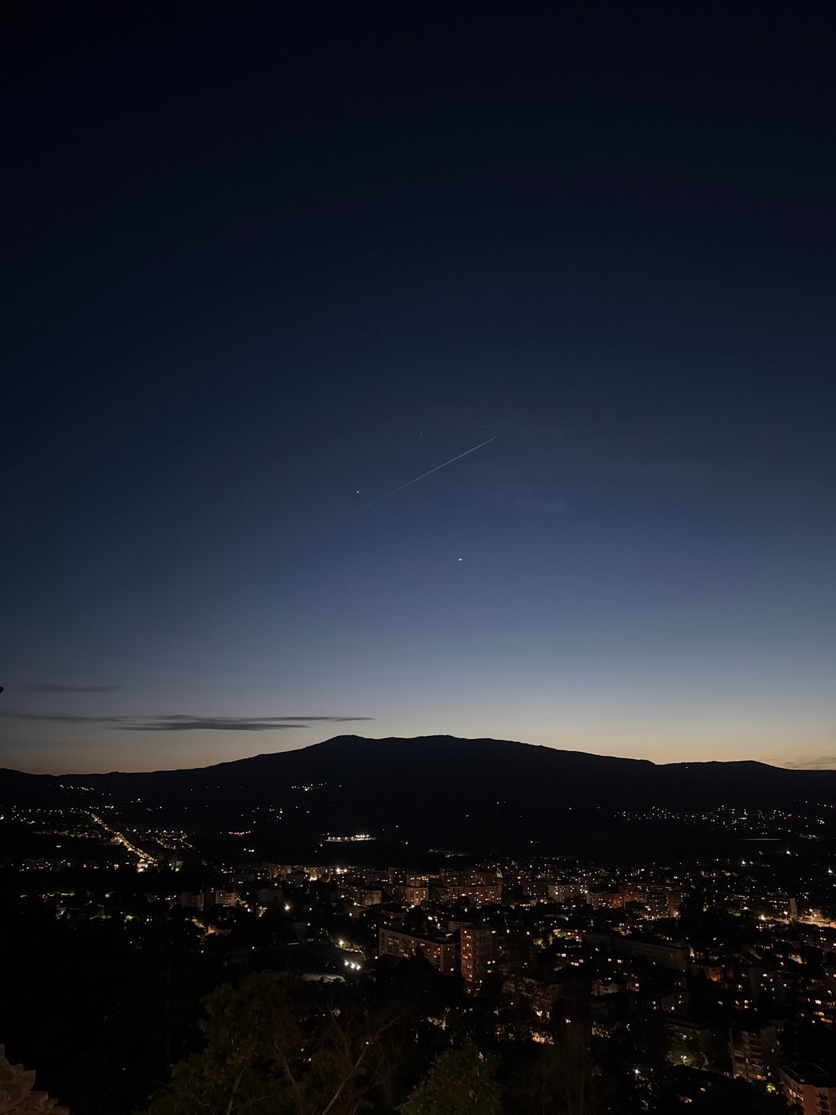 City lights illuminate mountain valley at dusk