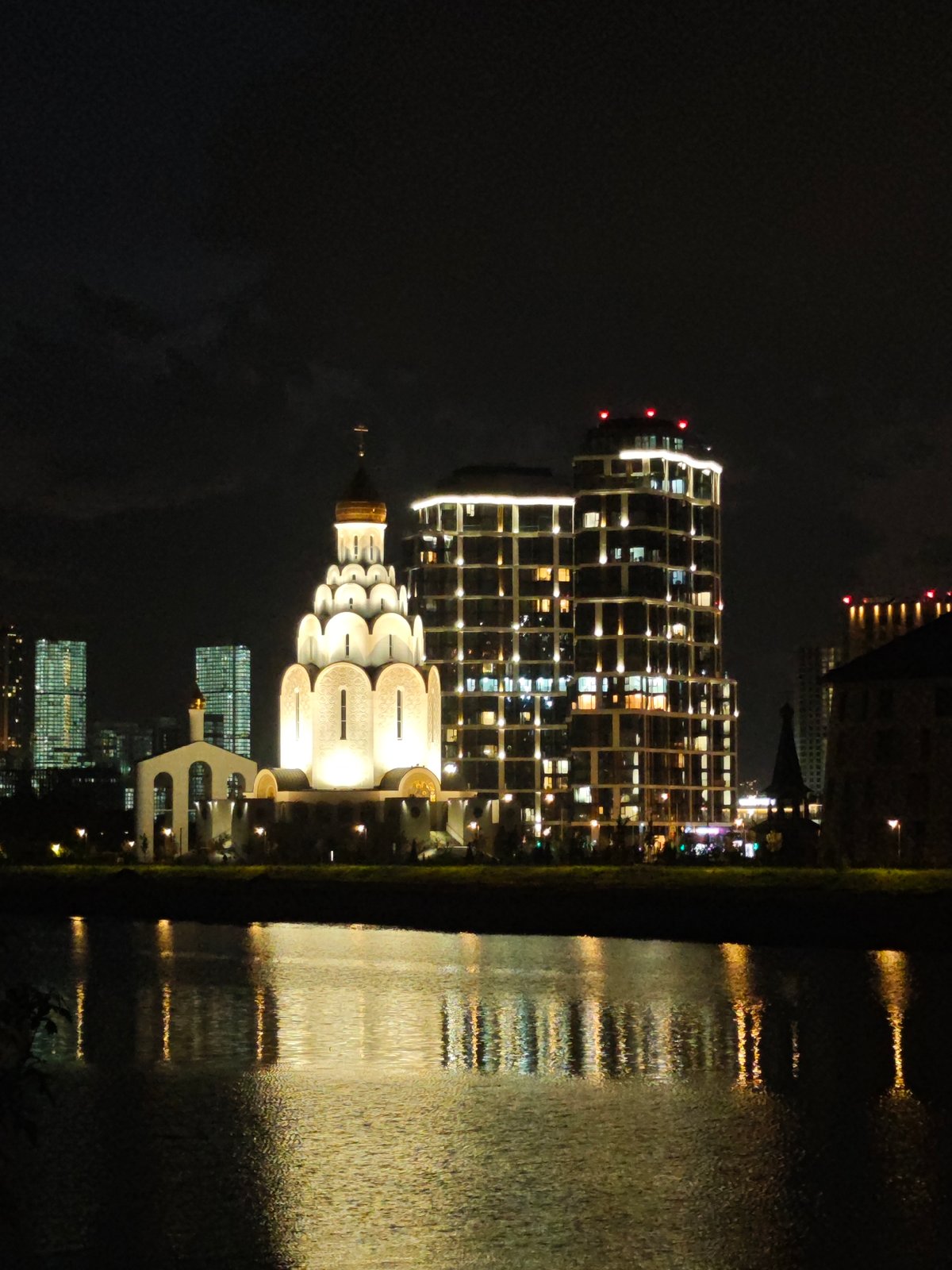 Nighttime waterfront lights reflected across water observed by witness