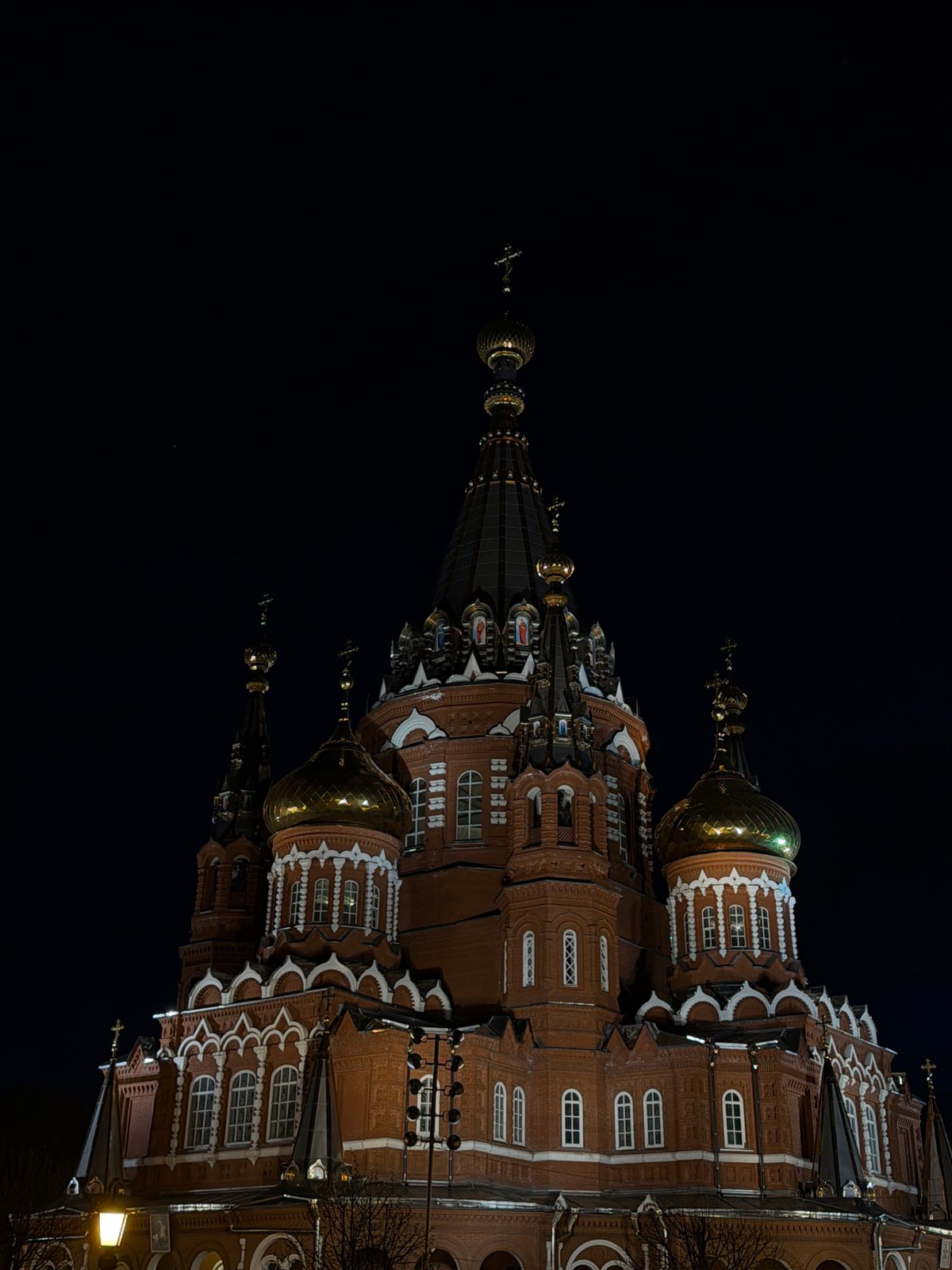 Evening pedestrian spotted near illuminated cathedral in Izhevsk