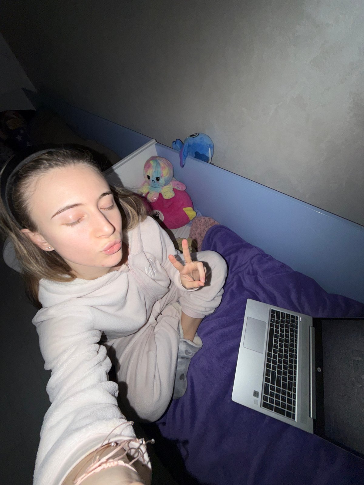 Woman relaxes with laptop and stuffed animals in Plovdiv bedroom