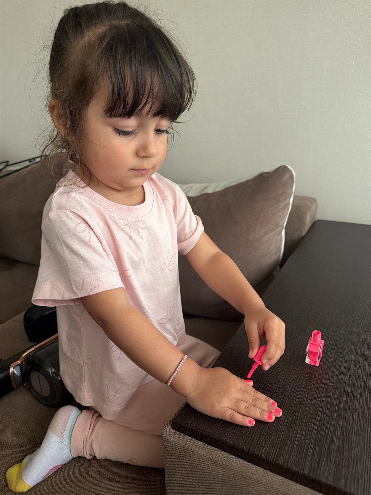 Young girl paints fingernails pink in Burgas home