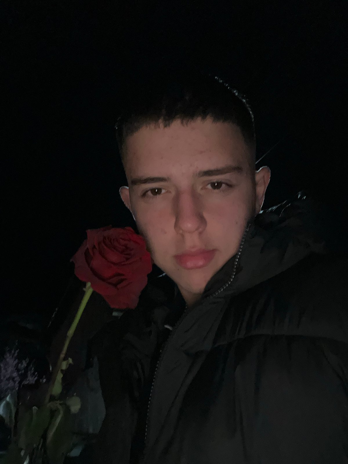 Person with red rose observed on wet street in Zlatograd