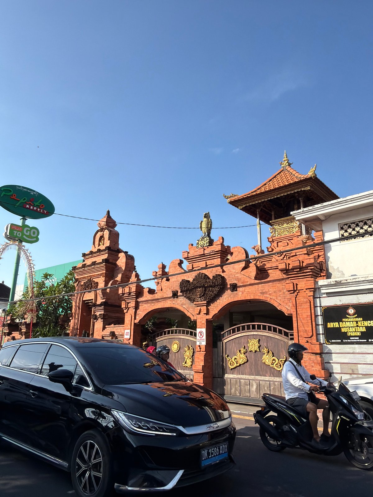 Traffic passes a ornate Balinese gate in Denpasar