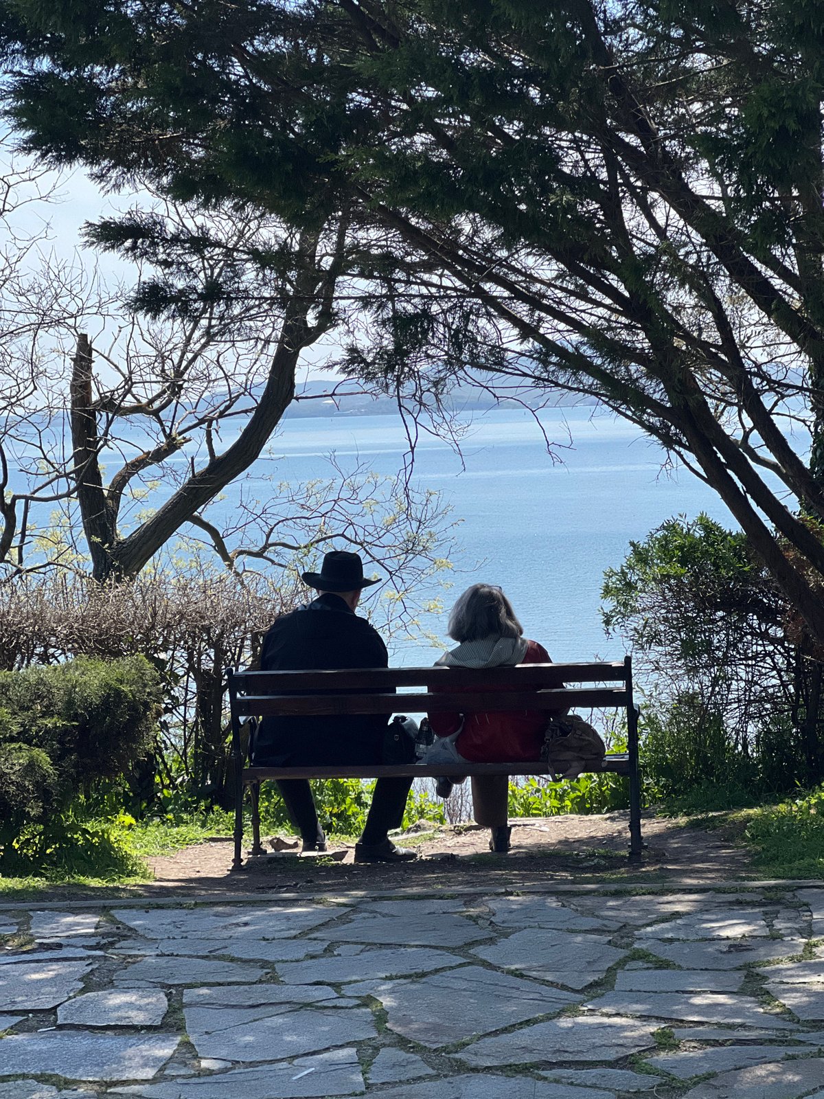 Two people sit on bench overlooking water in Burgas