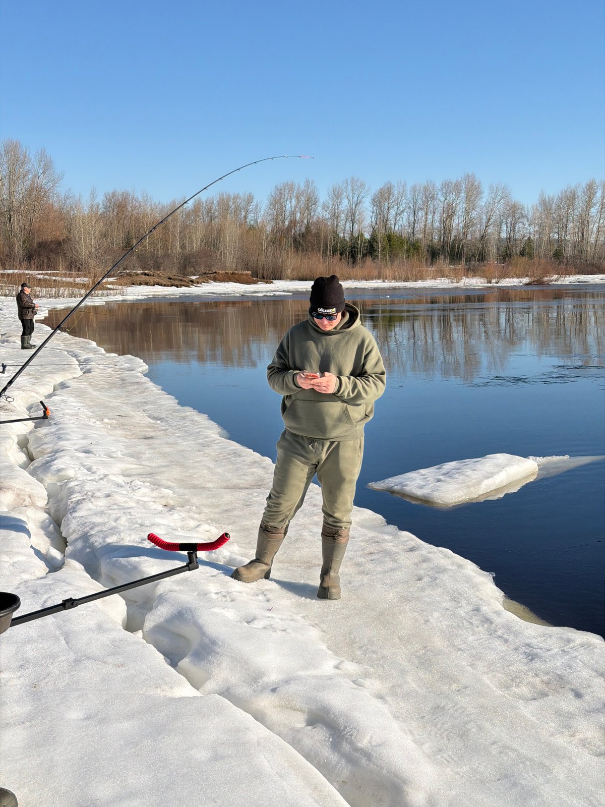 Two men ice fishing on frozen river in Chaikovsky, Russia