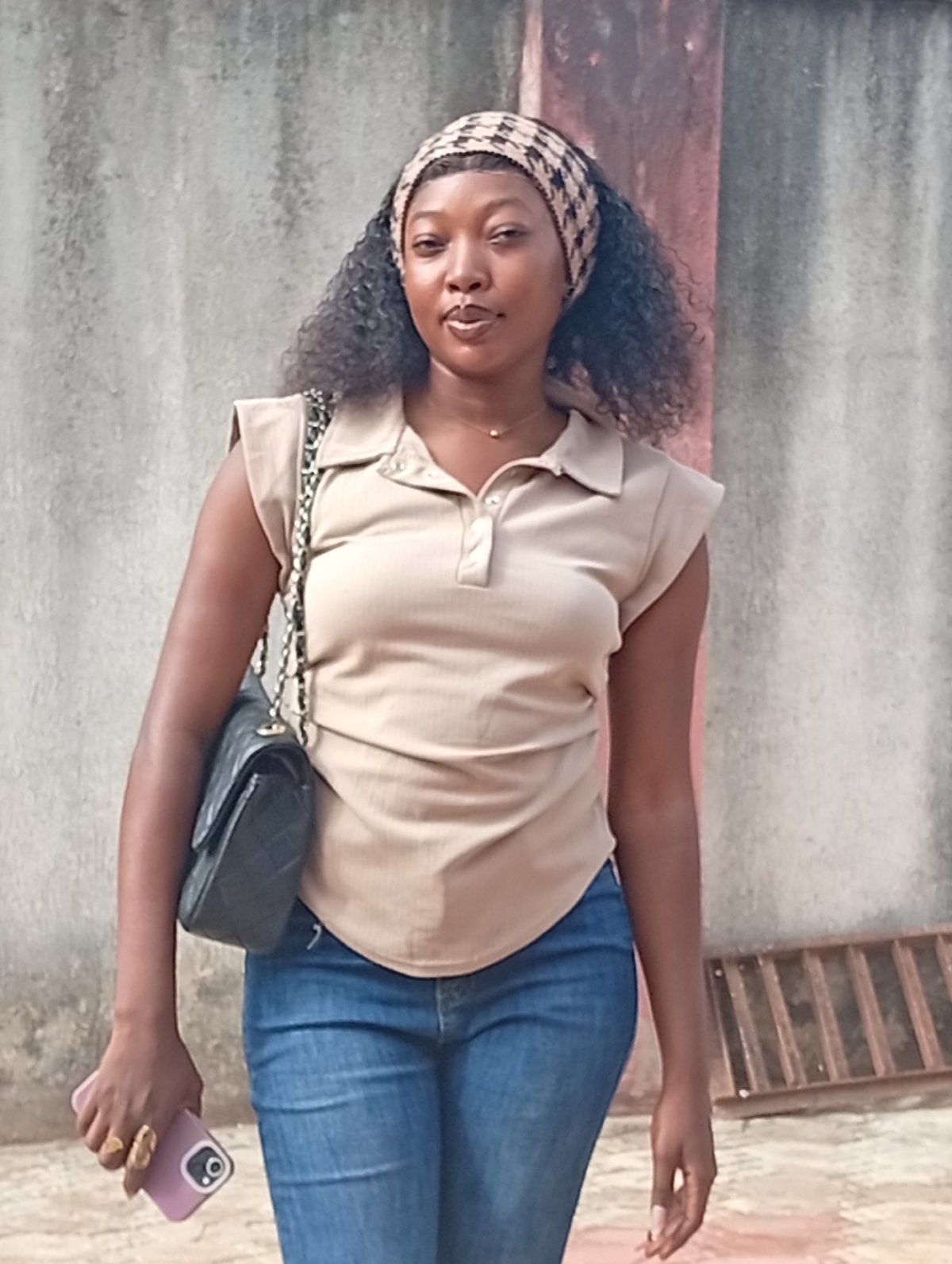 Woman photographed standing by concrete wall with smartphone