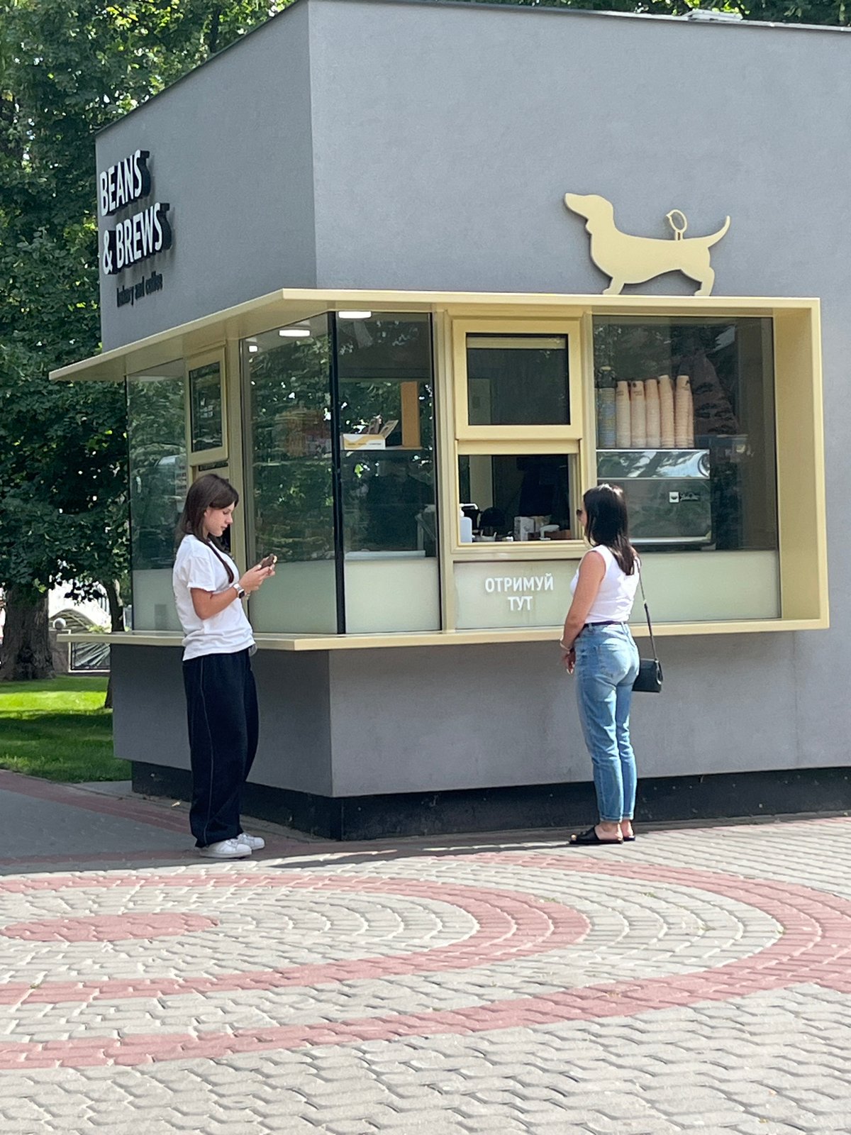 Coffee kiosk, open lawns, and a flower-ringed statue in a public park