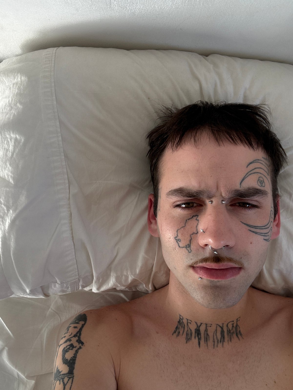 Tattooed individual rests on pillow in Buenos Aires