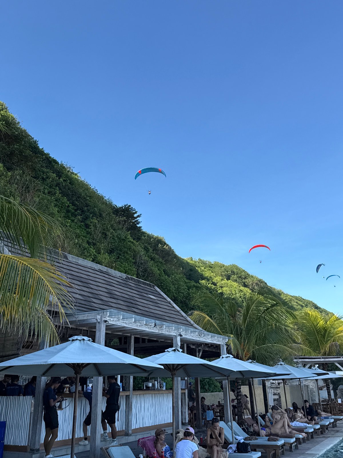 Paragliders soar over Kuta Selatan beaches under clear skies