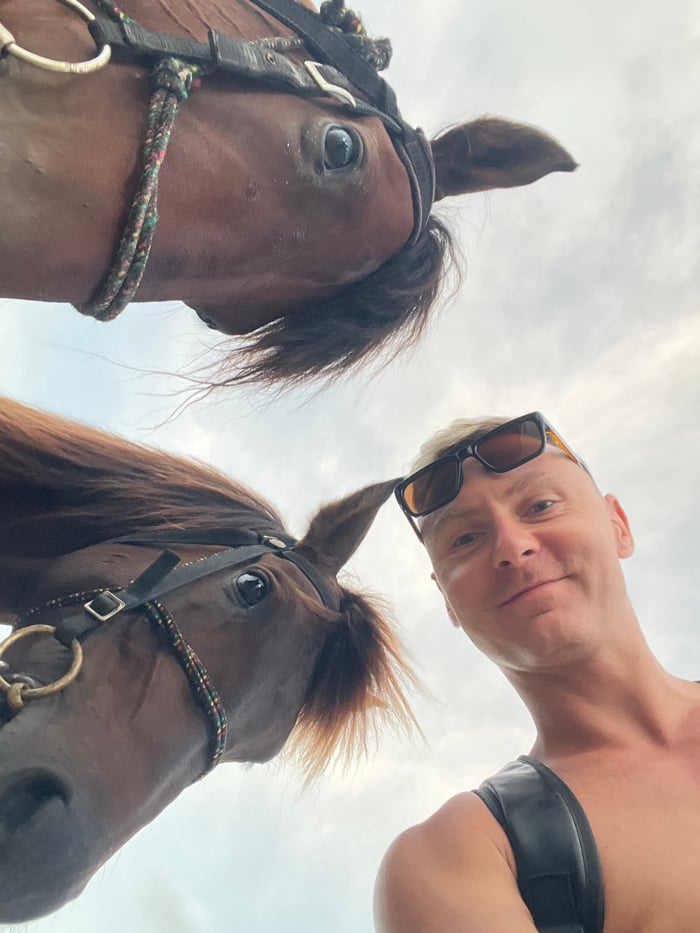 Tourist documents beach day with horses in Jimbaran, Indonesia