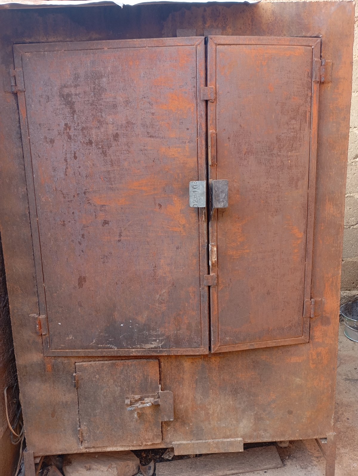 Heavily rusted double-door metal cabinet, worn and weathered