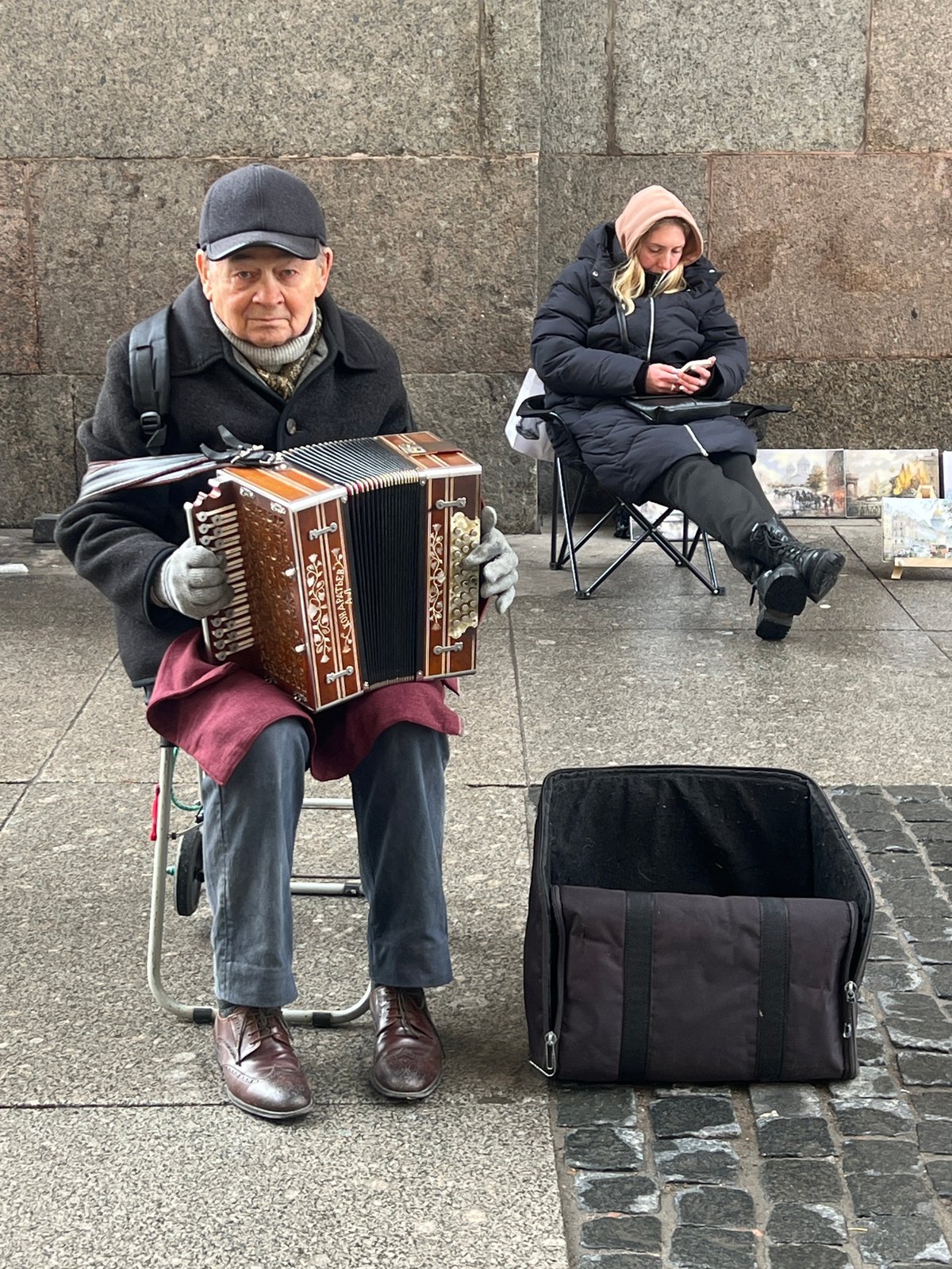 Street musician performs accordion amid paintings in Saint Petersburg