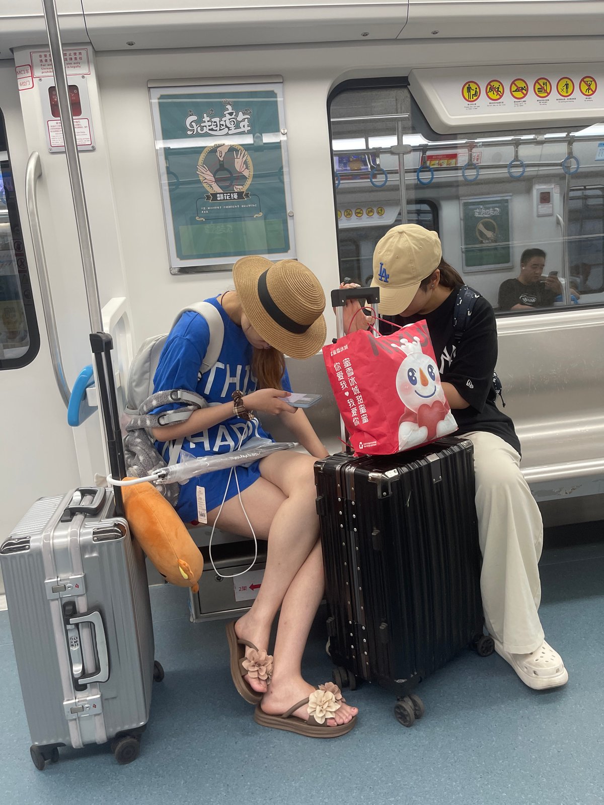 Quiet subway ride, phones out, straw hat in frame