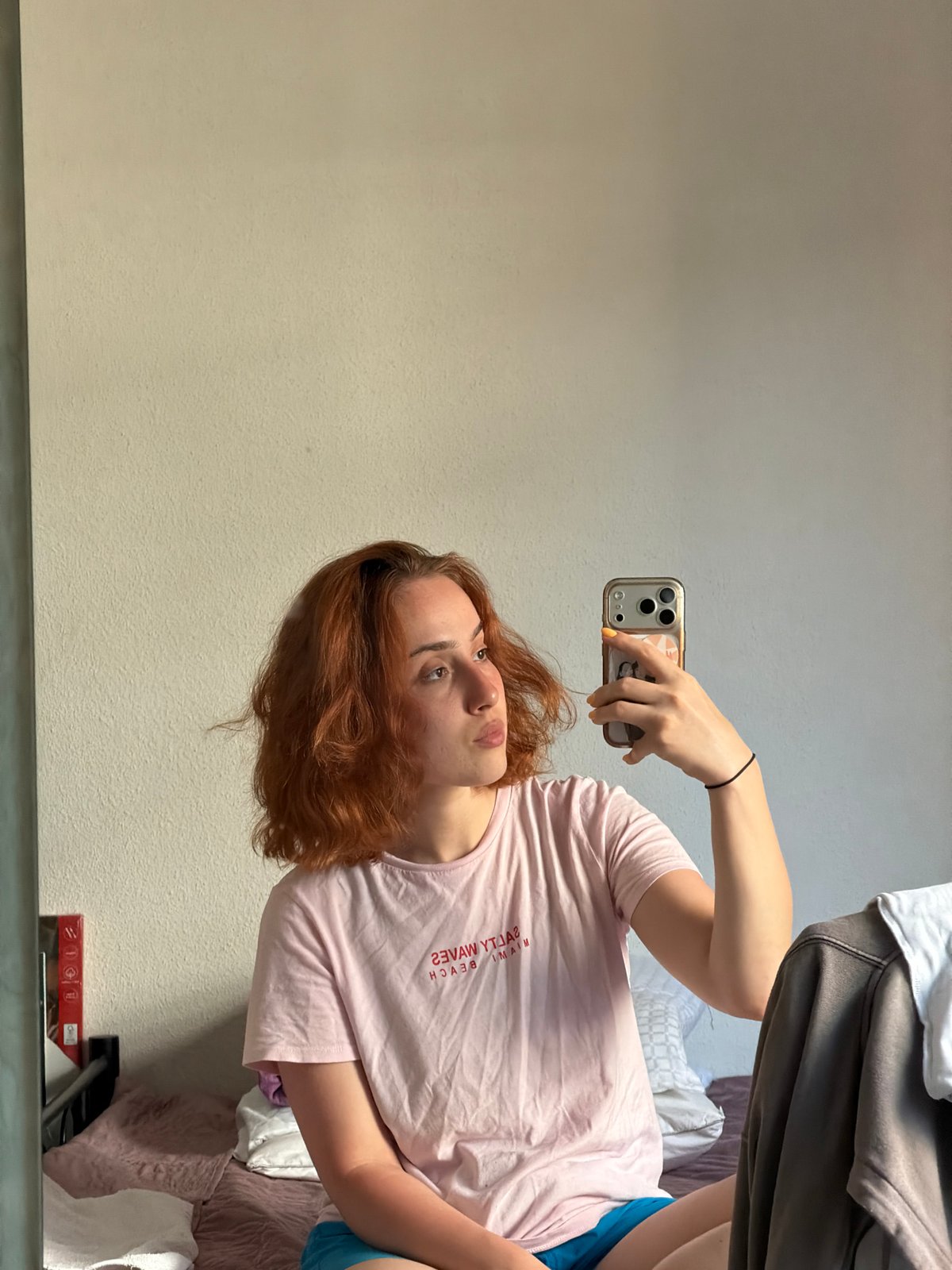 Mirror selfies in a Strasbourg bedroom, pink Miami Beach tee