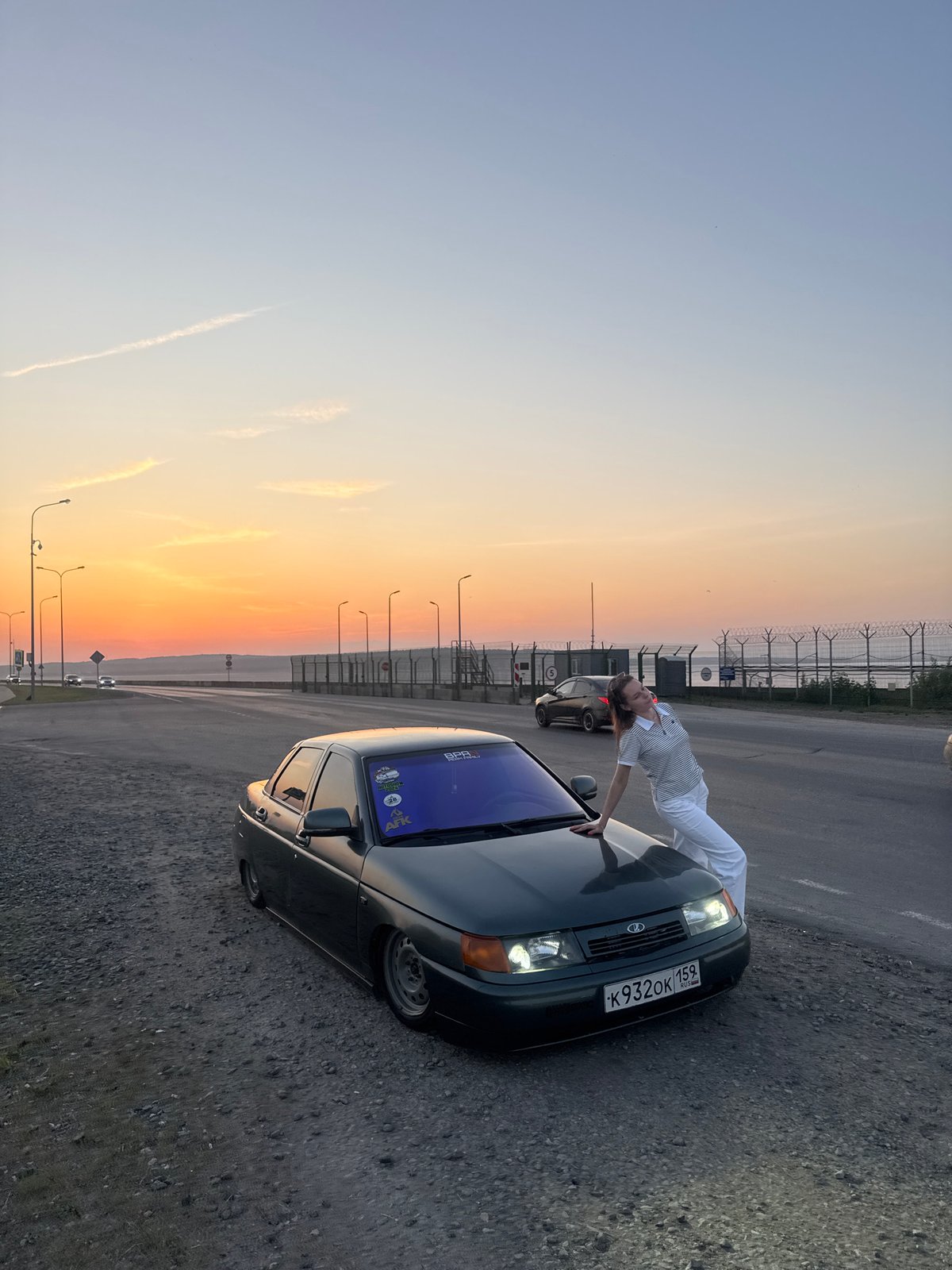 Woman poses with car during sunset in Chaikovsky, Russia
