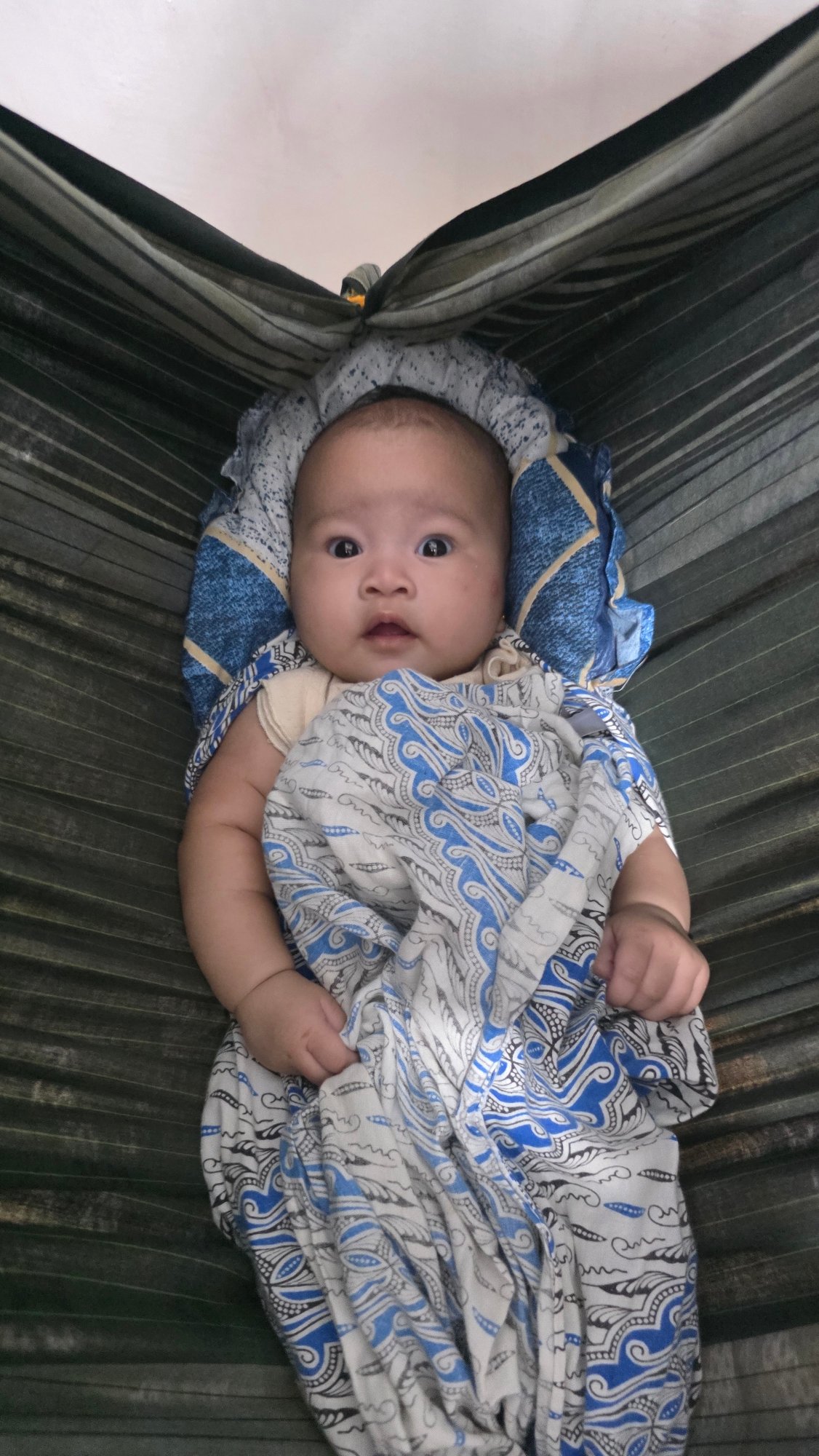 Baby rests peacefully in hammock in Lhokseumawe, Indonesia