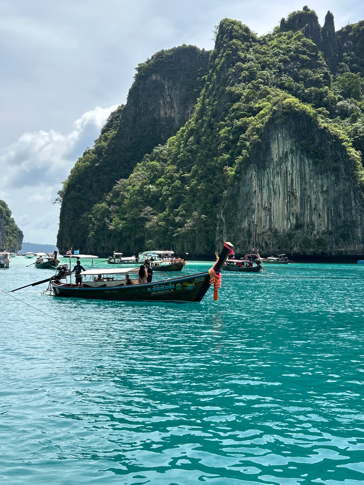 Boats and swimmers in Ao Nang's limestone-framed bay