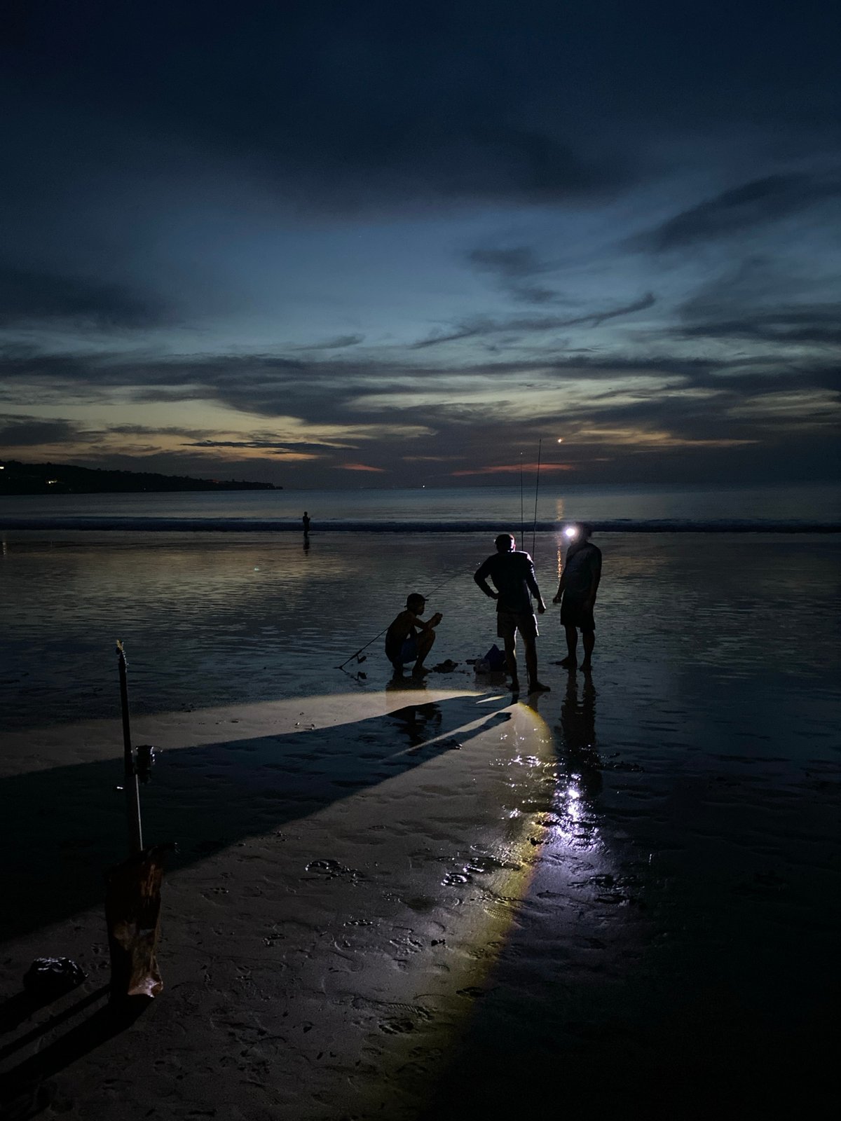 Evening beachgoers gather with flashlight in Kuta Selatan