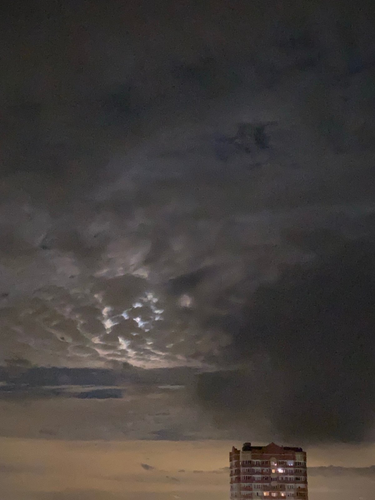 Light breaks through dark clouds in nighttime sky