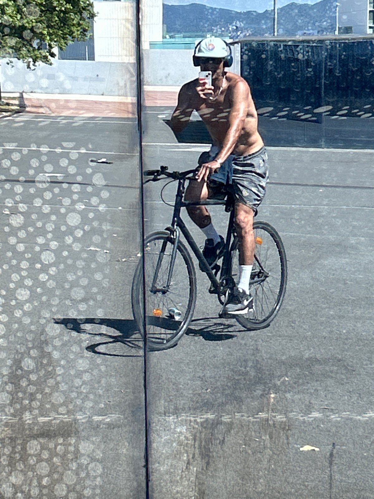 Cyclist rides through Barcelona while using smartphone and wearing headphones