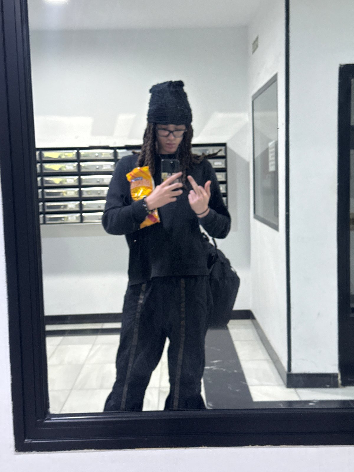 Person takes mirror selfies in Madrid apartment building hallway