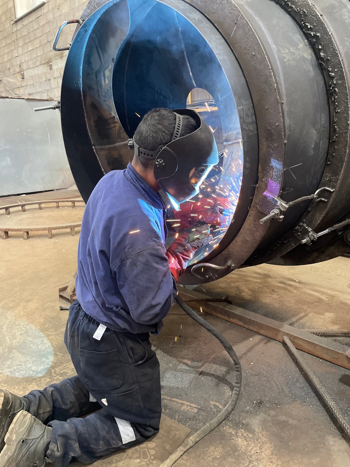 Welder performs arc welding in industrial workshop in Tomba