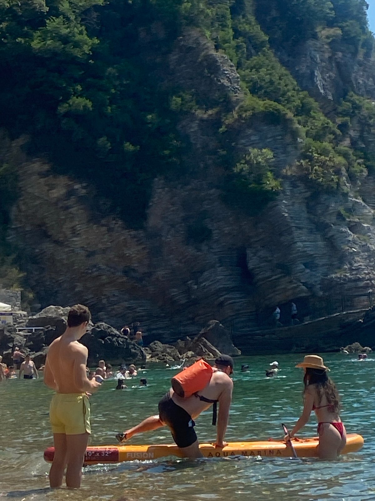 Paddleboards and pedal boats off Budva's rocky shore