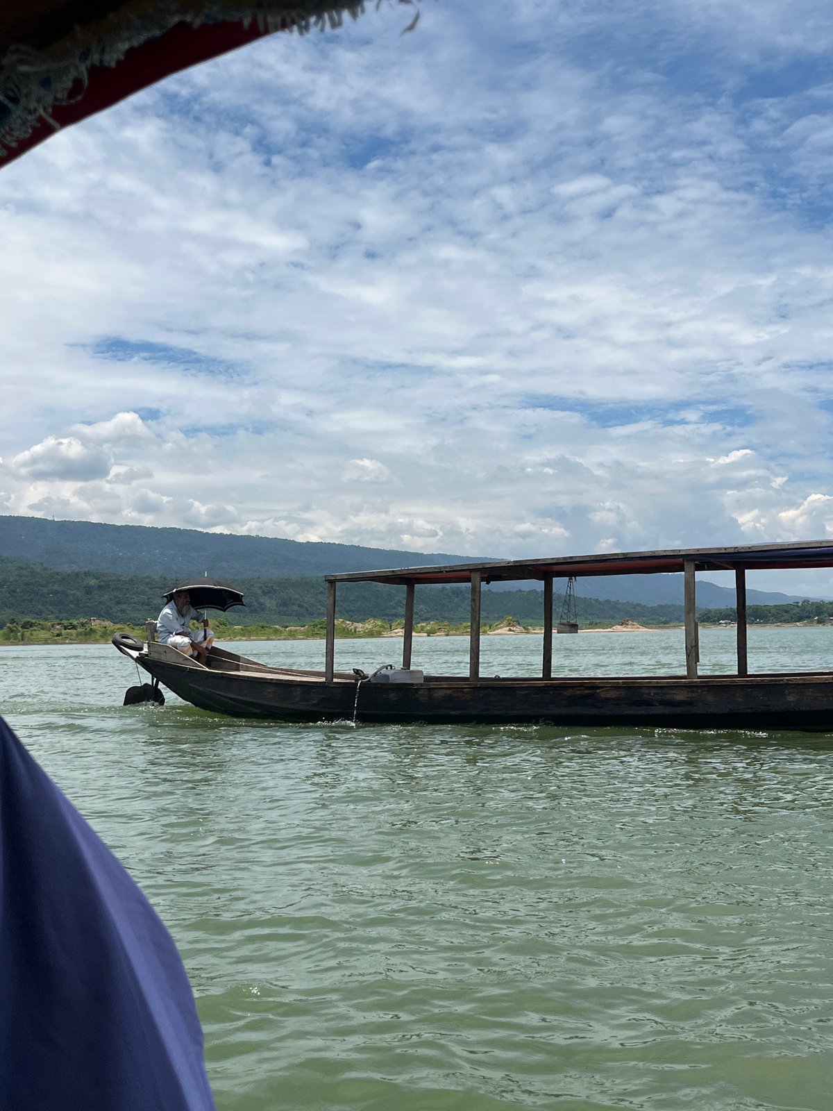 Boat ride along a green river through hilly northeast India