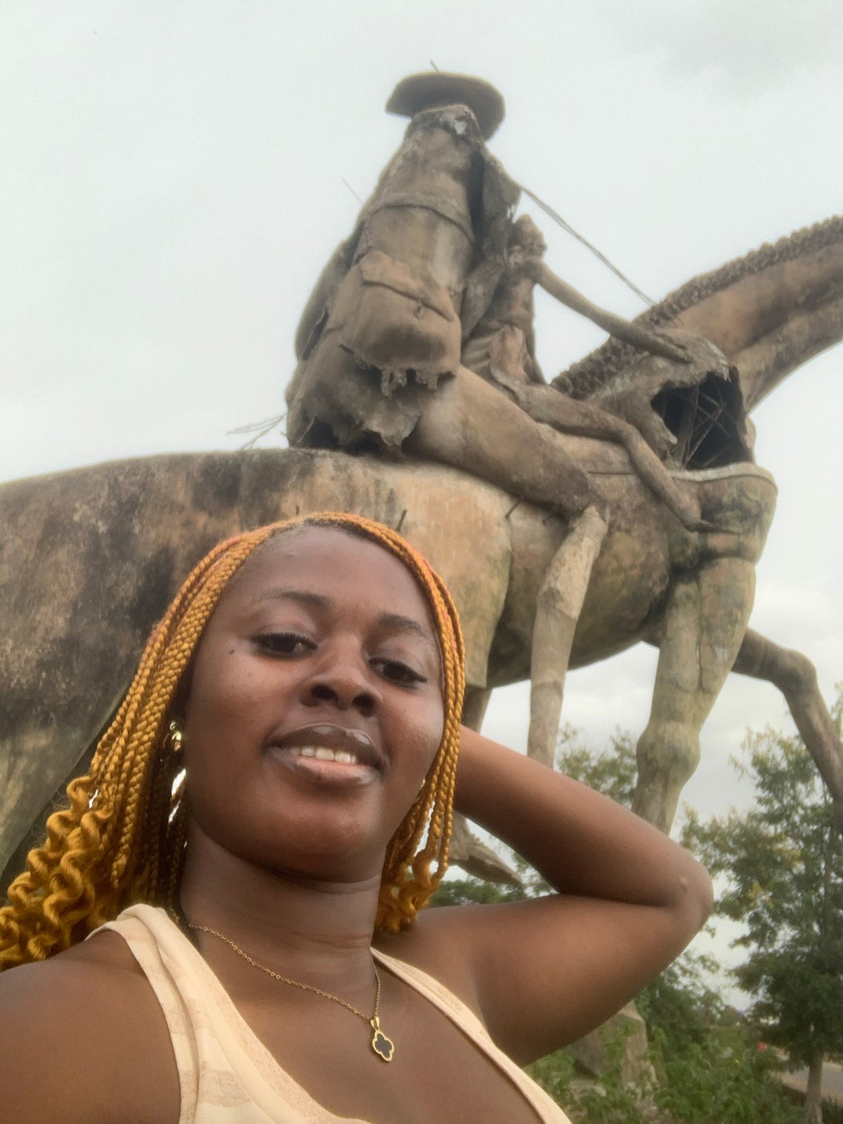 Woman photographs damaged cowboy statue in Gura Top, Nigeria