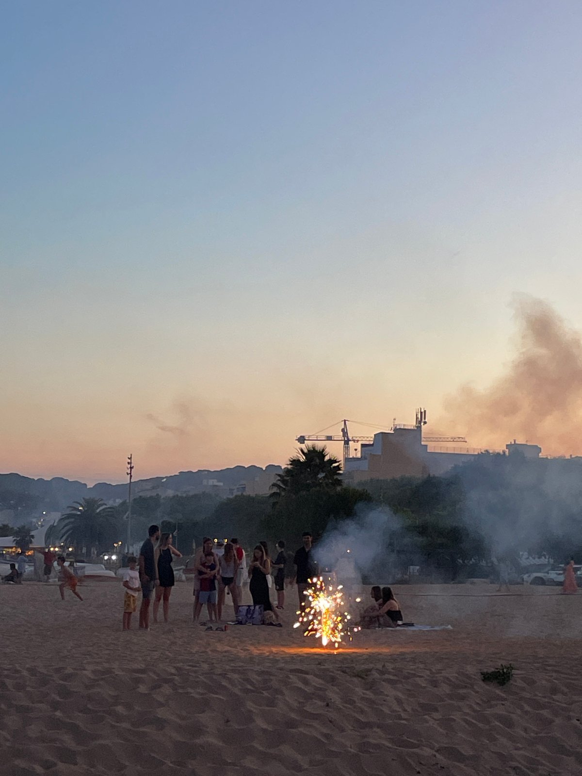 Fireworks and beach crowds at dusk in Calella, Spain