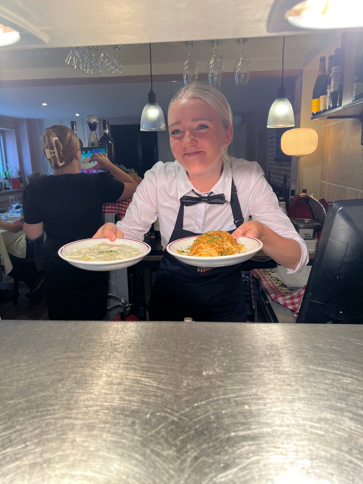 Server carries plated dishes through a Guildford restaurant