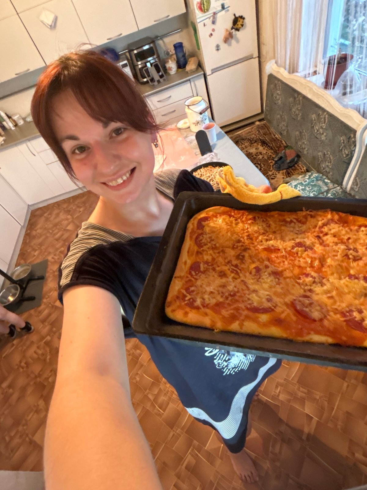 Woman holds homemade pizza in Russian kitchen