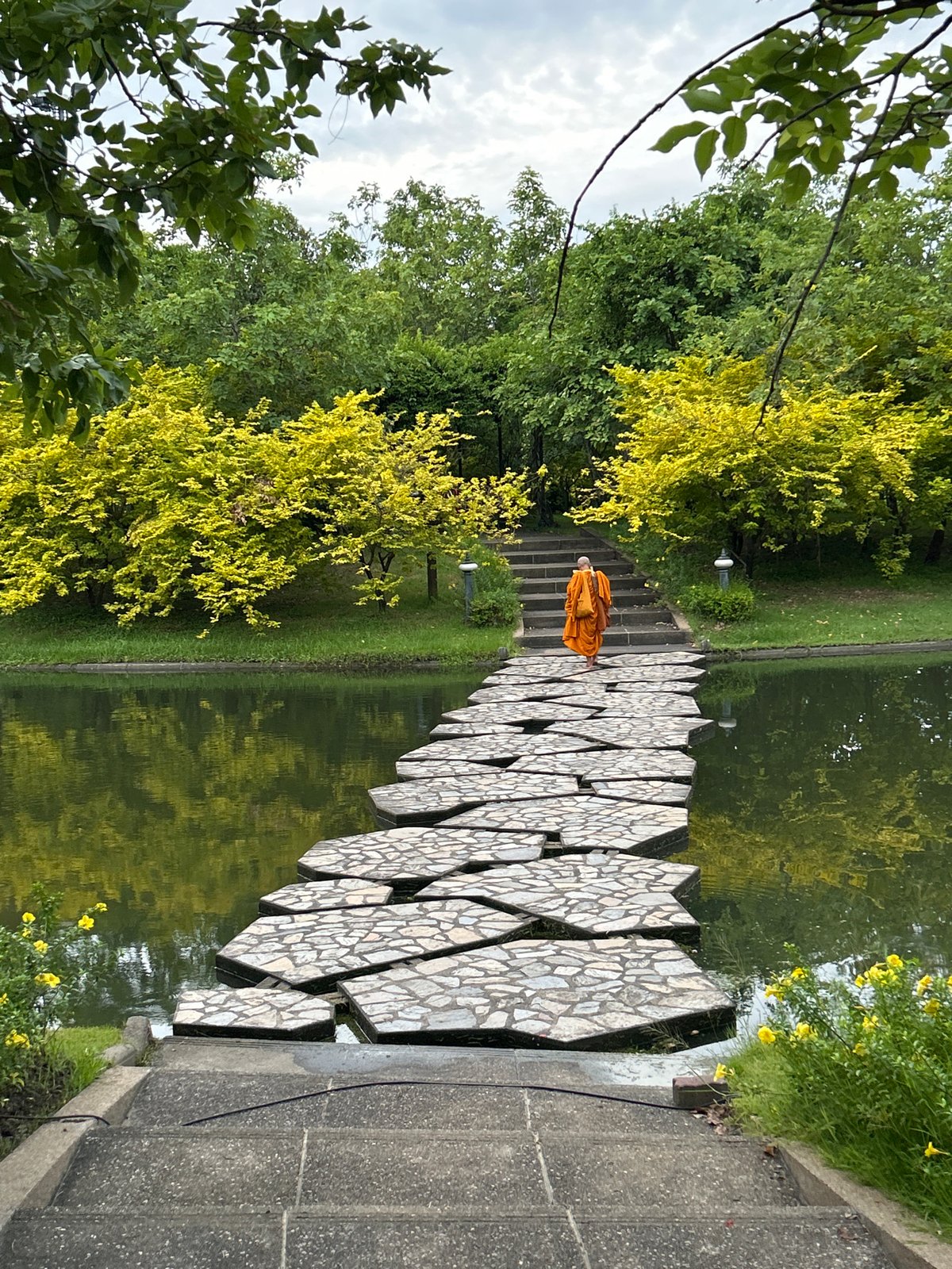 Monk walks stone water path in Bangkok park