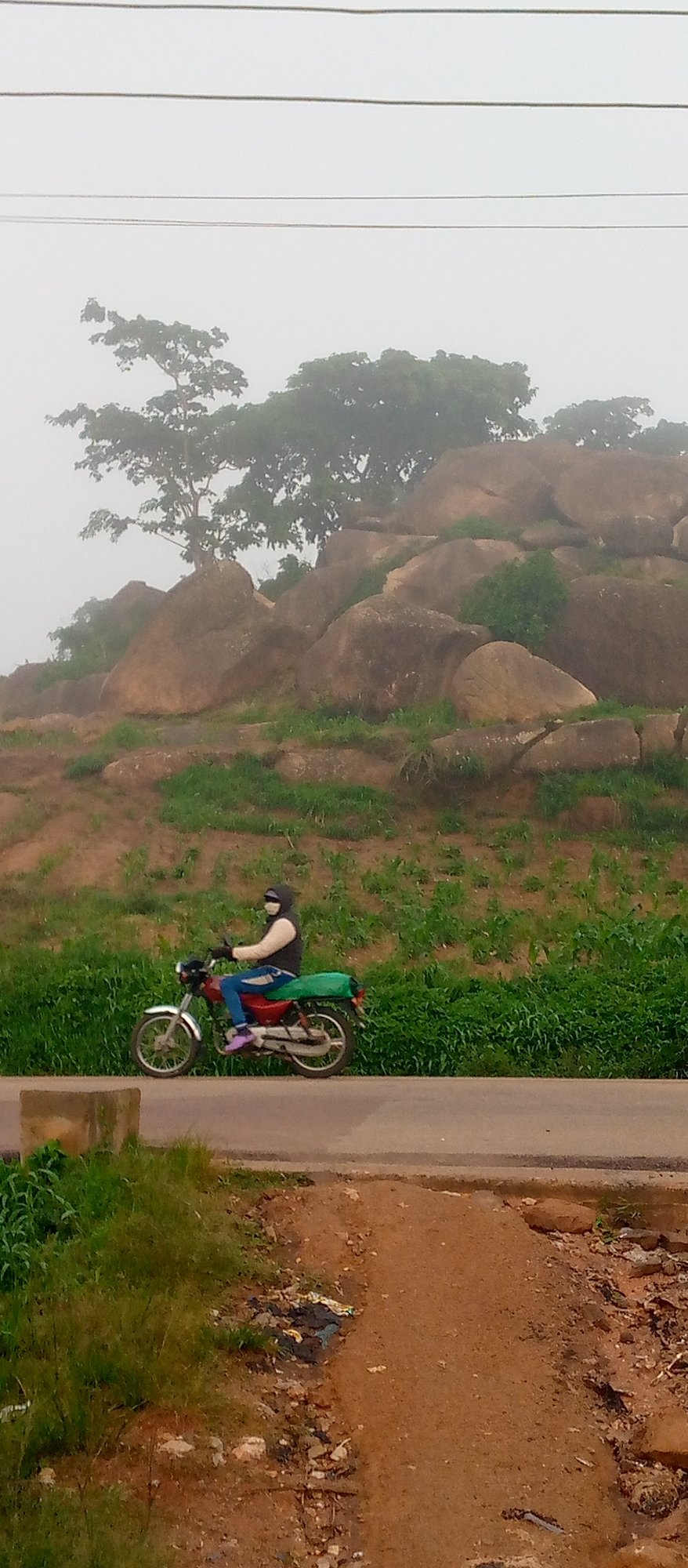 Foggy rural landscape with boulders, a littered river, and farmland
