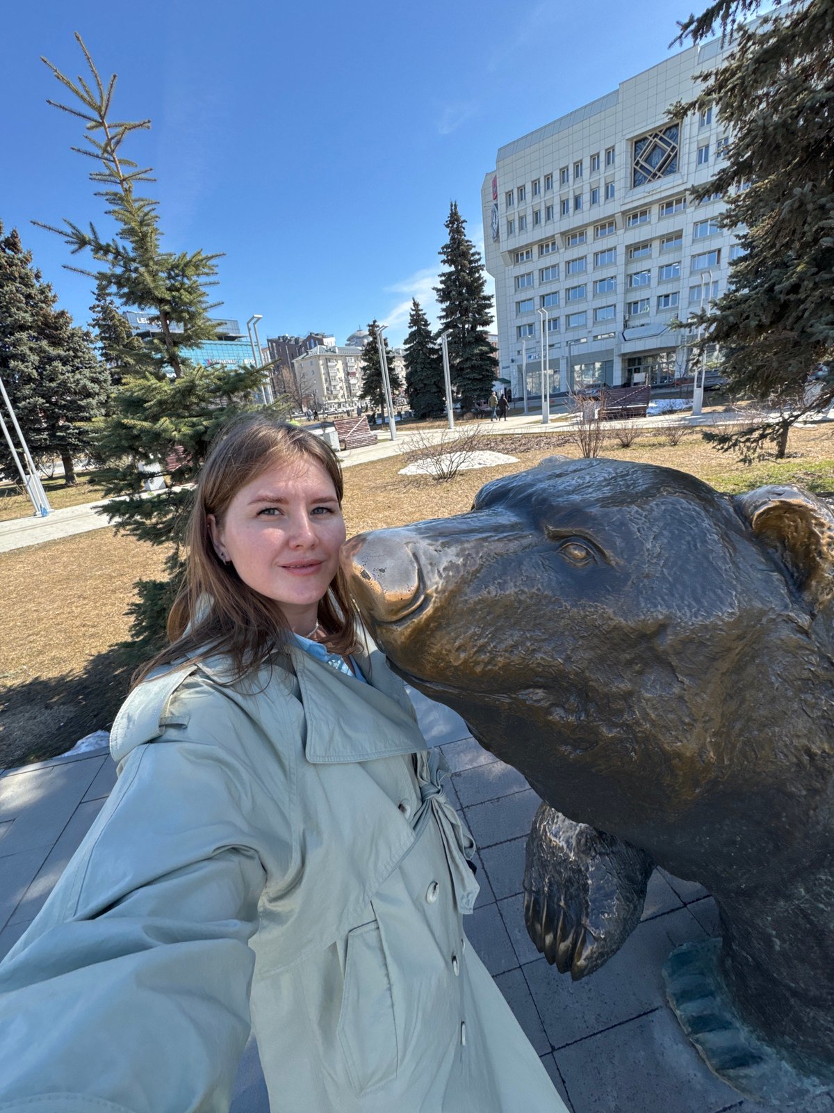 Tourist poses with bronze bear statue in Perm