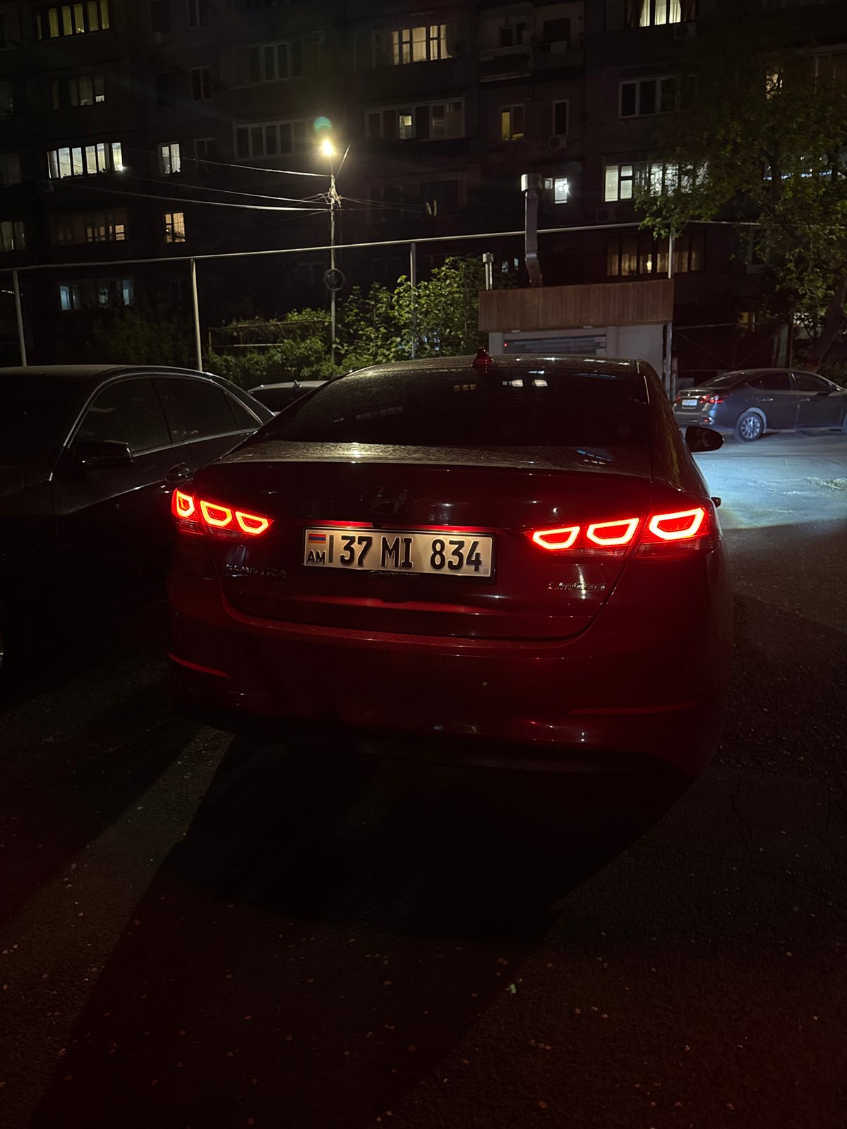 Maroon car with illuminated taillights parked on Yerevan street
