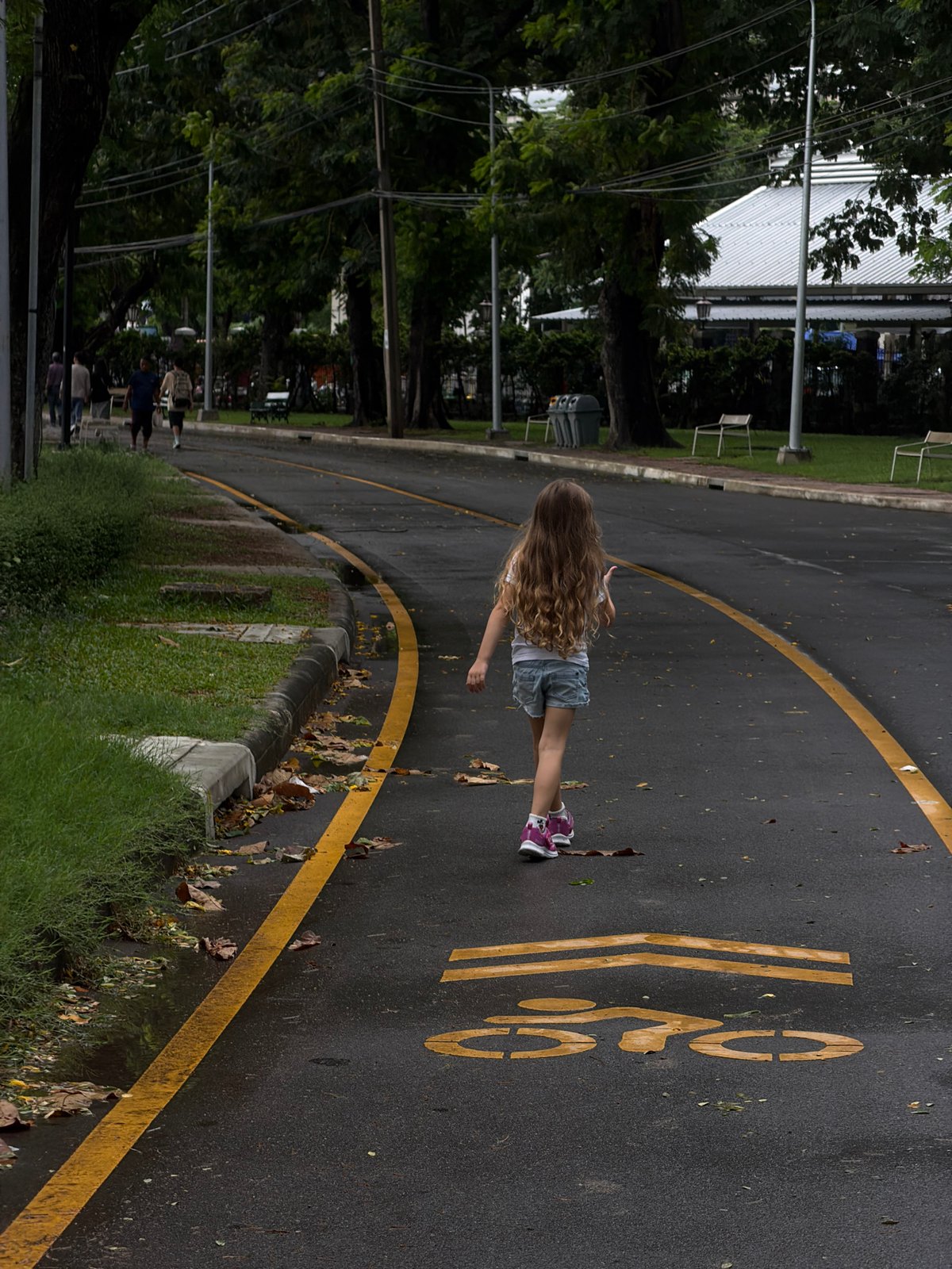 Child walks through Bangkok park on rainy morning