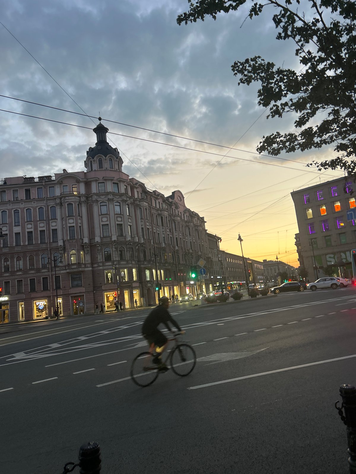 Dusk traffic moves past ornate buildings on a historic city street