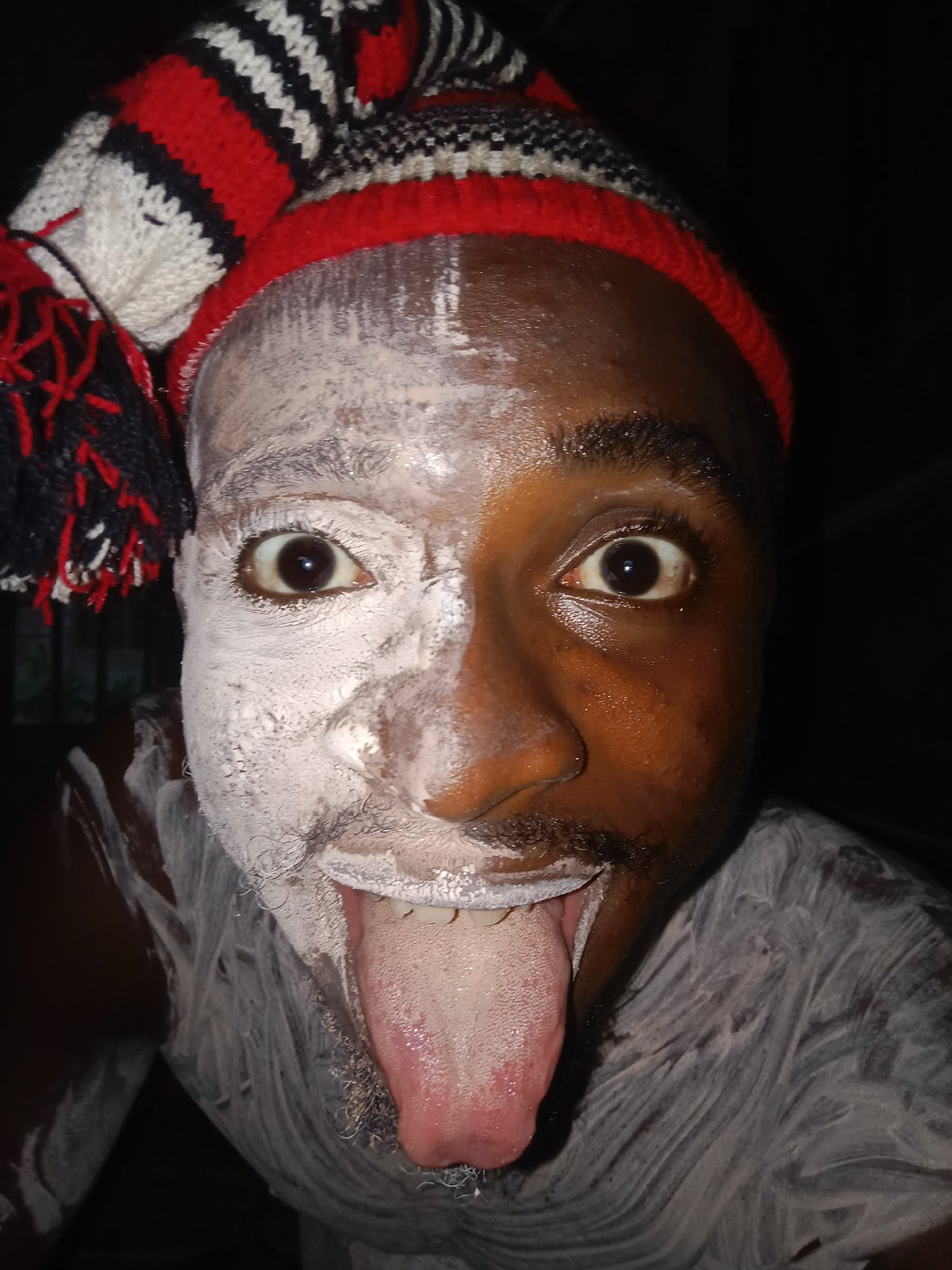 Man with white face paint documented in striped hat