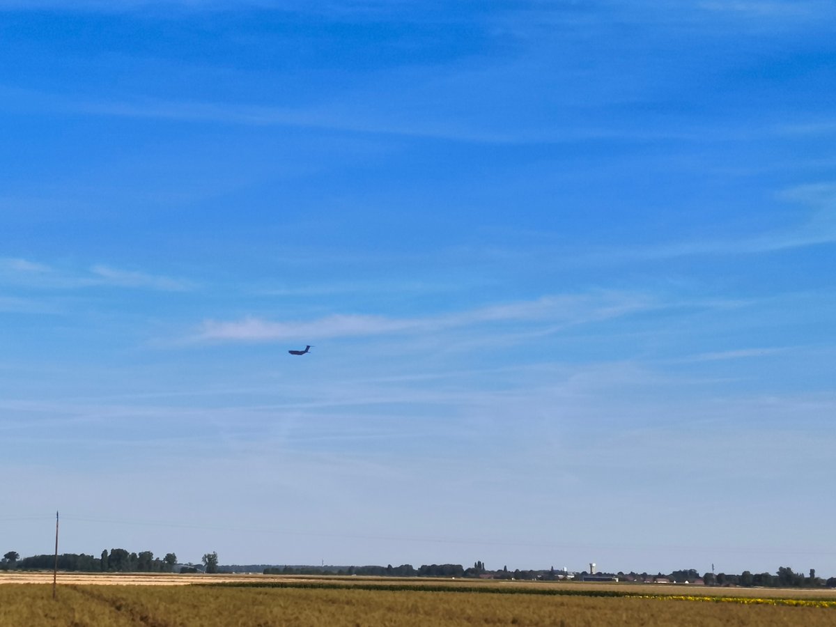 Airplane crosses clear skies over rural French countryside