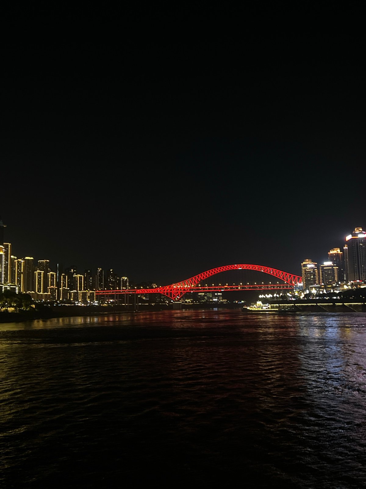 Red arch bridge glows over the Yangtze River at night