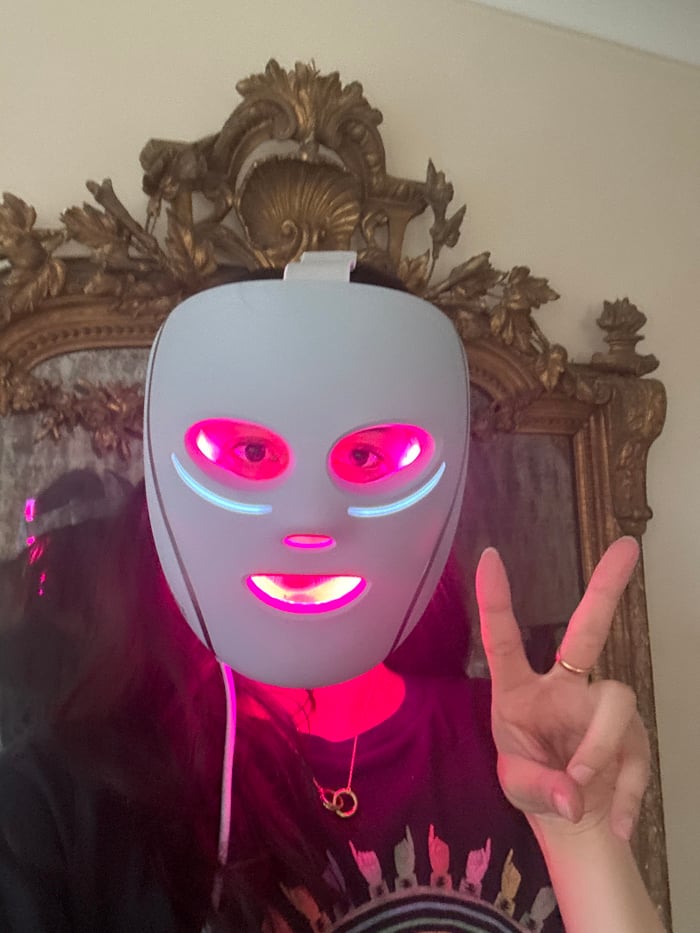 Person documents morning routine wearing glowing LED face mask