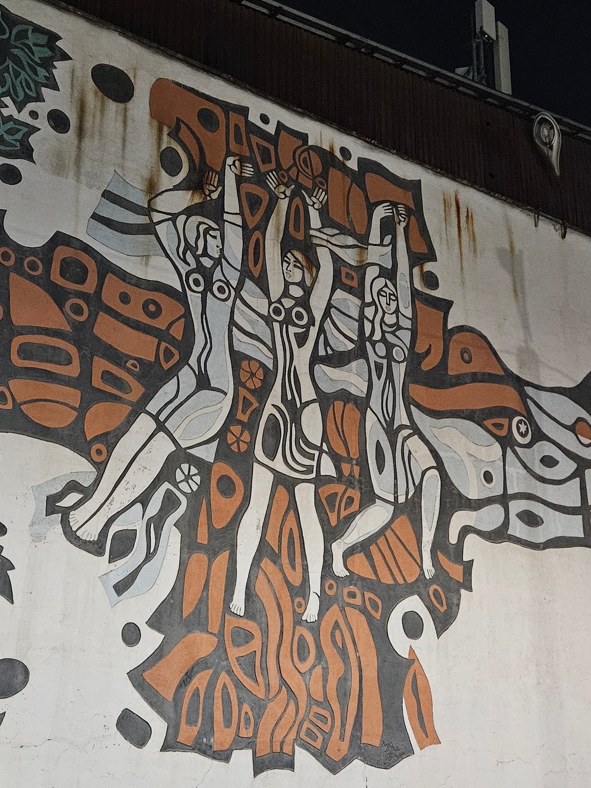 Stylized mural with three figures on an Almaty building wall