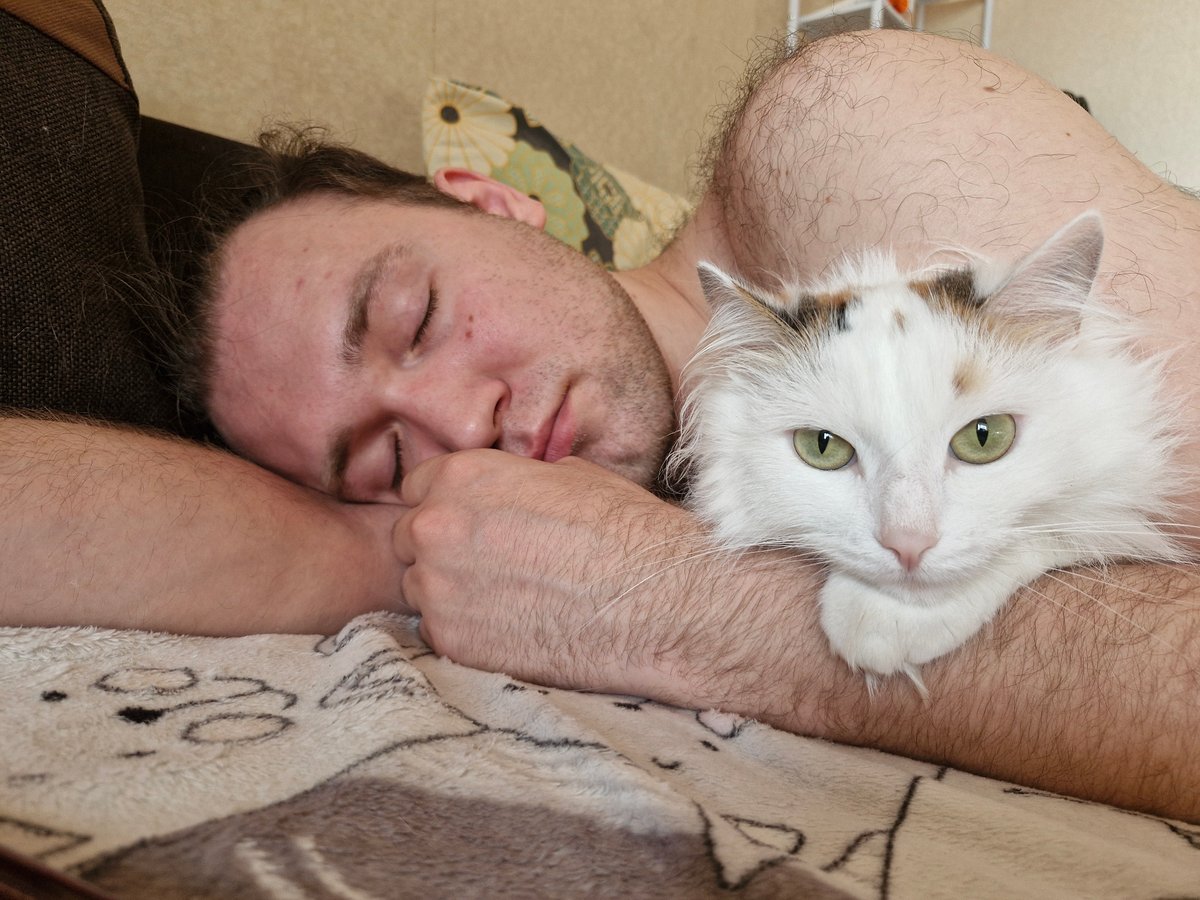 Man naps with cat on cartoon blanket in Yekaterinburg